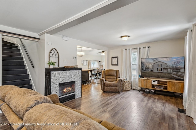 living area with a ceiling fan, a fireplace, stairway, and wood finished floors