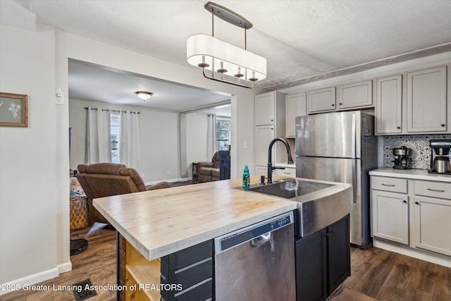 kitchen featuring appliances with stainless steel finishes, dark wood-style flooring, a center island with sink, and open floor plan