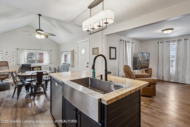 kitchen featuring dishwasher, butcher block countertops, open floor plan, dark cabinets, and a sink