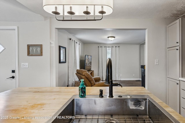 kitchen with open floor plan, a sink, a textured ceiling, and wooden counters