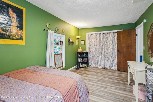 bedroom featuring a textured ceiling, wood finished floors, and baseboards