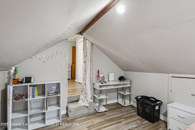 interior space featuring lofted ceiling, baseboards, and wood finished floors