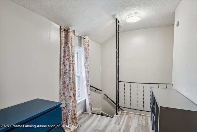 full bath featuring a textured ceiling, plenty of natural light, wood finished floors, and shower / tub combo with curtain