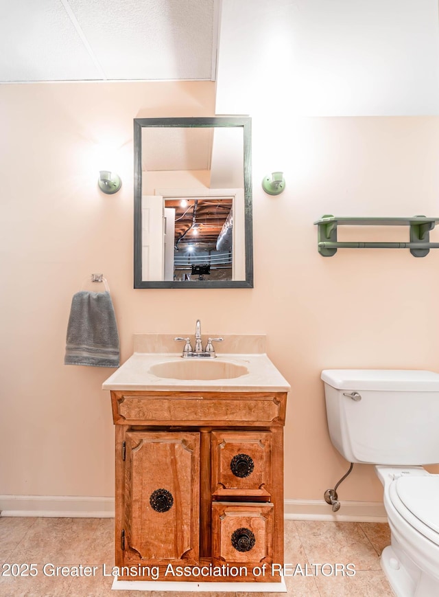 bathroom featuring vanity, tile patterned flooring, toilet, and baseboards