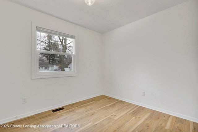 empty room featuring light wood-style floors, visible vents, and baseboards