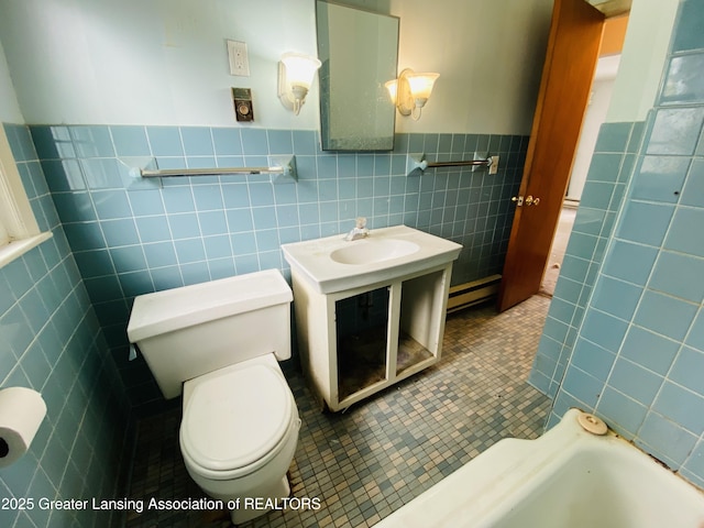 bathroom with a wainscoted wall, tile walls, toilet, vanity, and tile patterned flooring