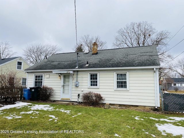 view of front of property featuring a chimney, fence, a front lawn, and roof with shingles