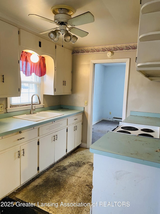 kitchen featuring light countertops, baseboard heating, white cabinetry, ceiling fan, and a sink