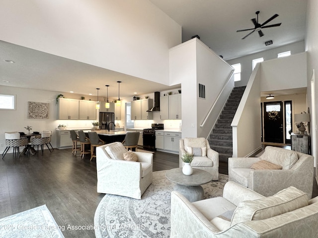 living area with recessed lighting, visible vents, stairway, a towering ceiling, and dark wood-type flooring