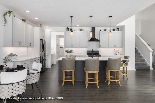 kitchen featuring wall chimney exhaust hood, light countertops, dark wood finished floors, and stainless steel appliances