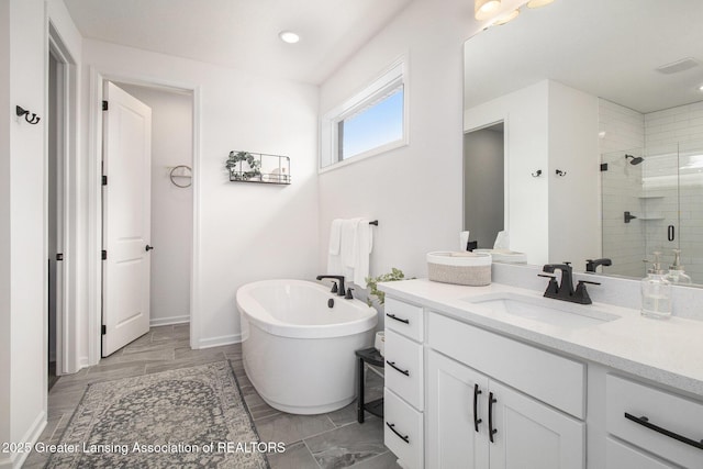 full bathroom featuring recessed lighting, a stall shower, vanity, a freestanding tub, and baseboards