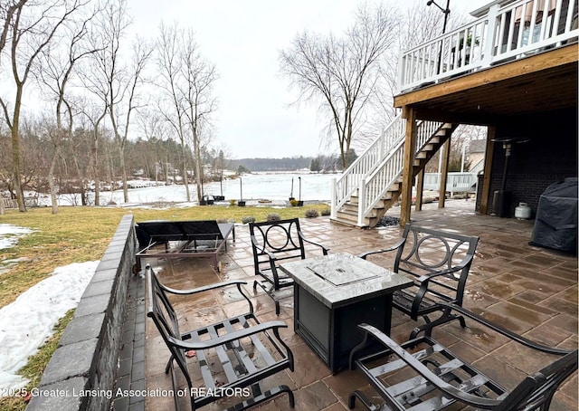 view of patio featuring an outdoor fire pit, stairway, and a deck with water view