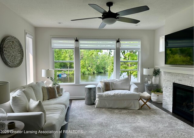 4125 Harbour Cv, Lansing, MI 48911 - living room featuring wood finished floors, a textured ceiling, plenty of natural light, a ceiling fan, and a fireplace with flush hearth