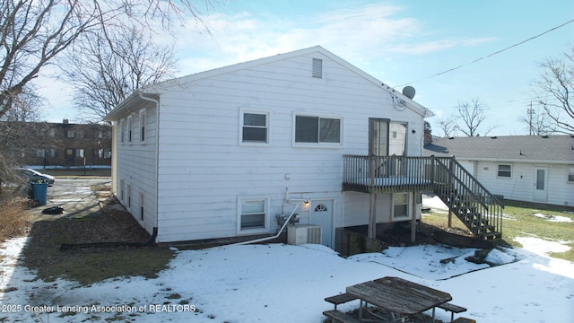 snow covered house with stairs and a wooden deck