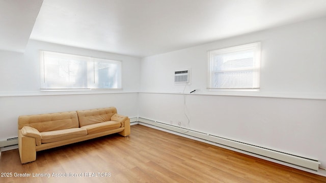 living area featuring a baseboard heating unit, light wood-type flooring, a wealth of natural light, and a wall mounted air conditioner