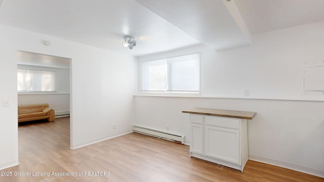 unfurnished room featuring light wood finished floors, a baseboard radiator, and baseboards