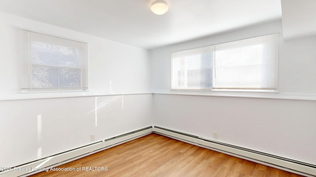 unfurnished room with a baseboard radiator and light wood finished floors