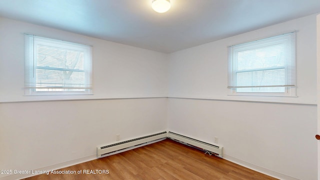 empty room featuring a baseboard heating unit and wood finished floors