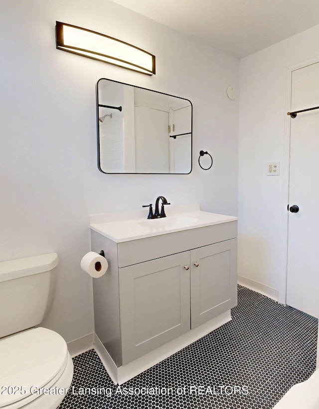 bathroom with tile patterned flooring, baseboards, vanity, and toilet