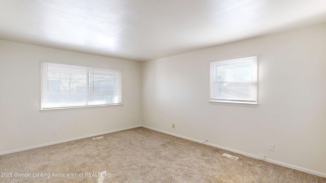 spare room with light carpet, baseboards, and visible vents