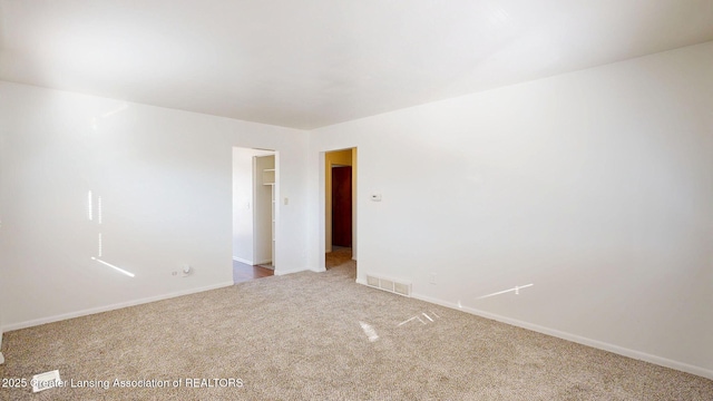 carpeted spare room featuring visible vents and baseboards