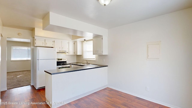 kitchen featuring a peninsula, a sink, baseboards, freestanding refrigerator, and stainless steel electric stove