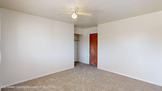 carpeted empty room with a ceiling fan and baseboards