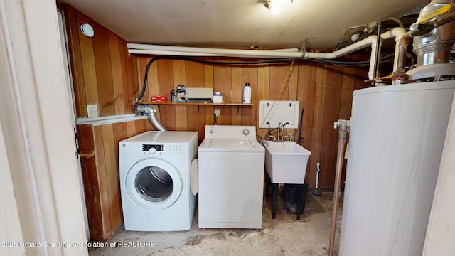 laundry area featuring water heater, laundry area, washer and clothes dryer, and wooden walls