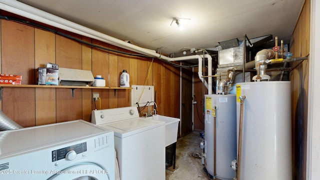 clothes washing area featuring gas water heater, independent washer and dryer, wooden walls, and laundry area