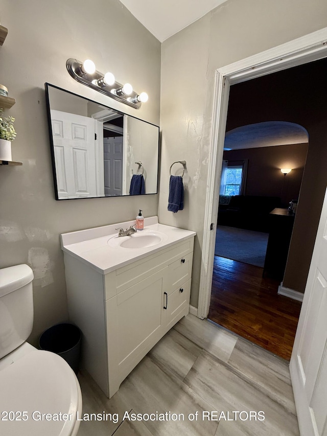 bathroom with baseboards, vanity, toilet, and wood finished floors