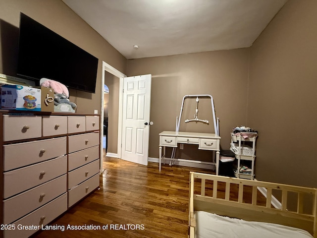 bedroom with dark wood-style floors and baseboards