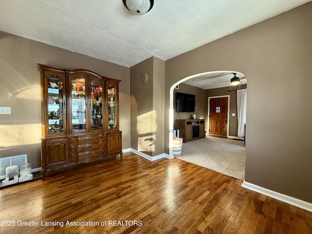 interior space with arched walkways, visible vents, baseboards, and wood finished floors