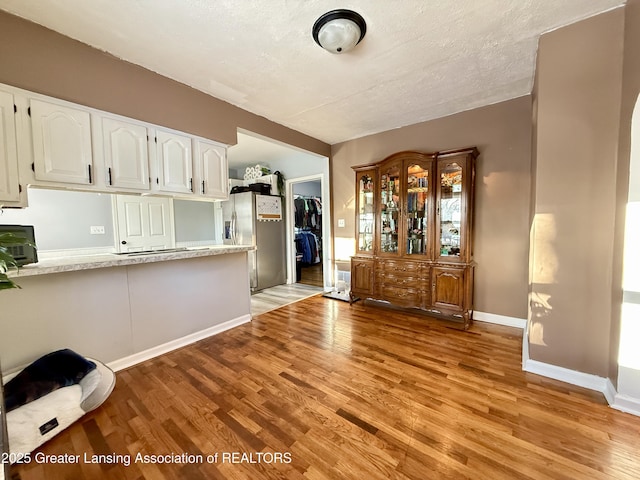 interior space with a textured ceiling, light wood finished floors, and baseboards