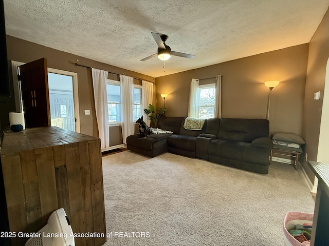 living room with ceiling fan, carpet floors, and a textured ceiling