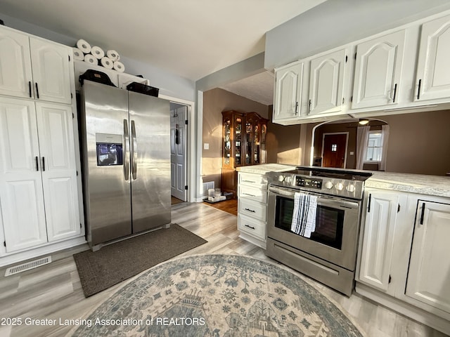 kitchen featuring stainless steel appliances, light countertops, visible vents, and white cabinetry