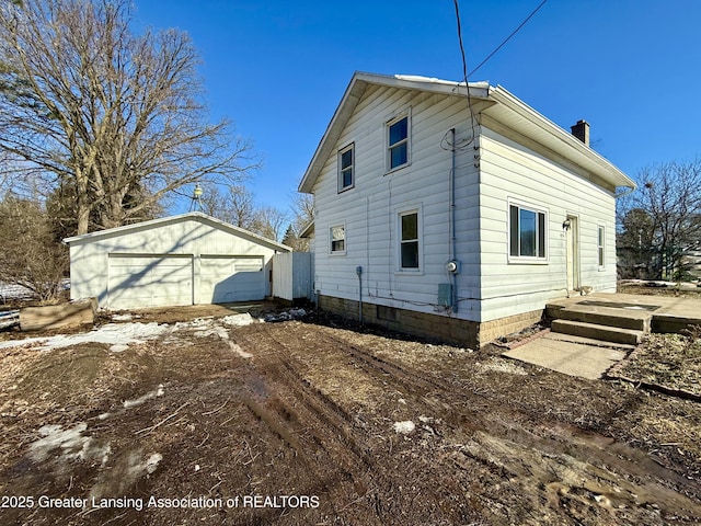 view of property exterior with an outbuilding, a chimney, and a detached garage