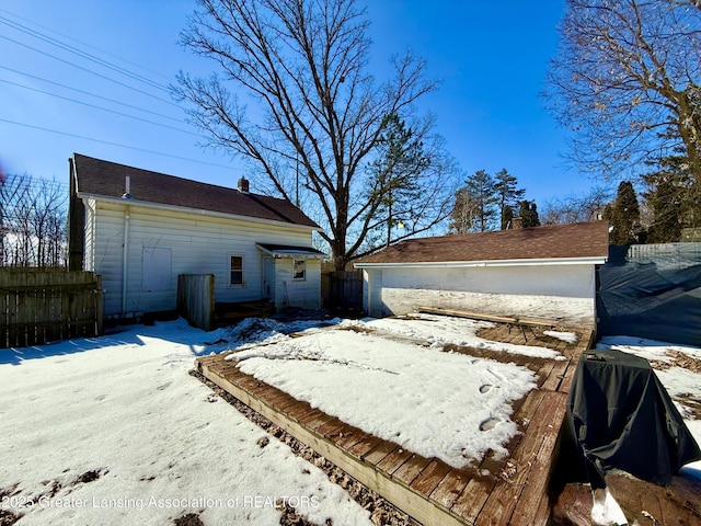 snow covered property with an outbuilding, a chimney, and fence