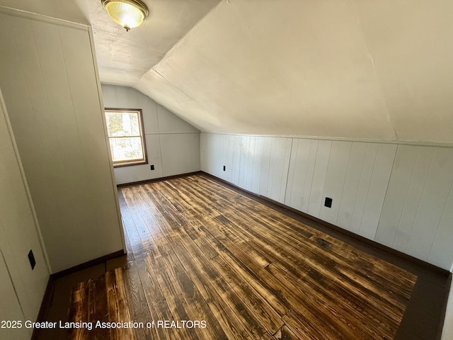 additional living space with dark wood-style floors, vaulted ceiling, and baseboards