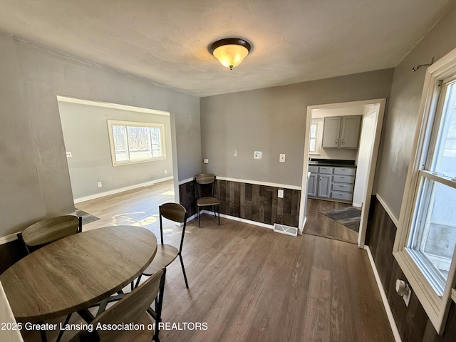 dining area featuring a wainscoted wall, visible vents, and dark wood finished floors