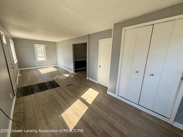 unfurnished bedroom featuring a closet, wood finished floors, and baseboards