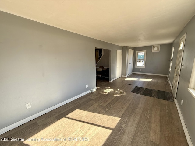 unfurnished living room with baseboards and wood finished floors