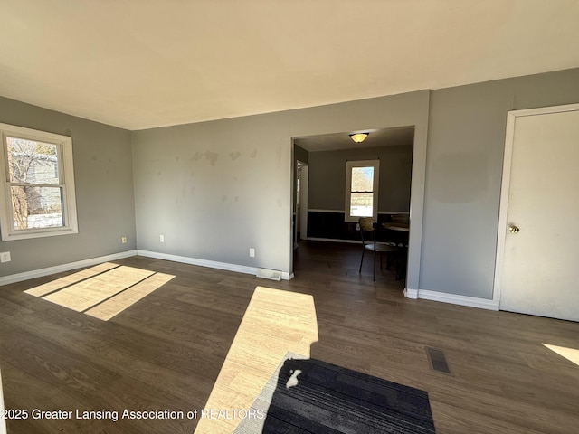 spare room featuring dark wood finished floors, visible vents, and baseboards