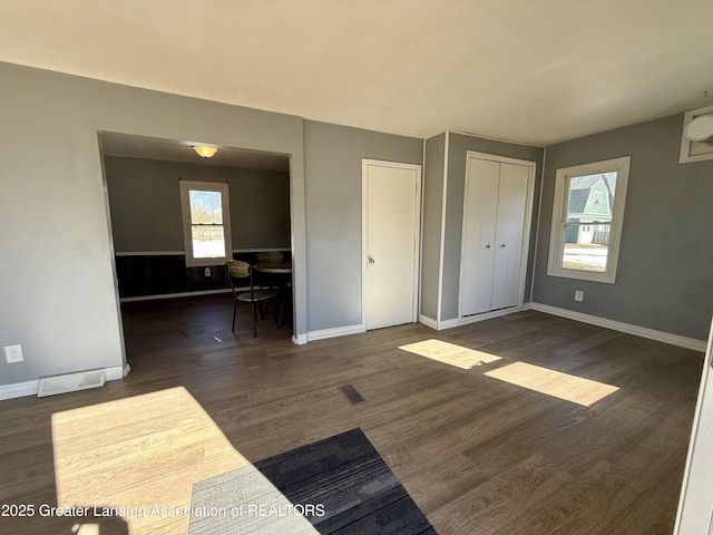 unfurnished bedroom with baseboards, multiple windows, visible vents, and wood finished floors