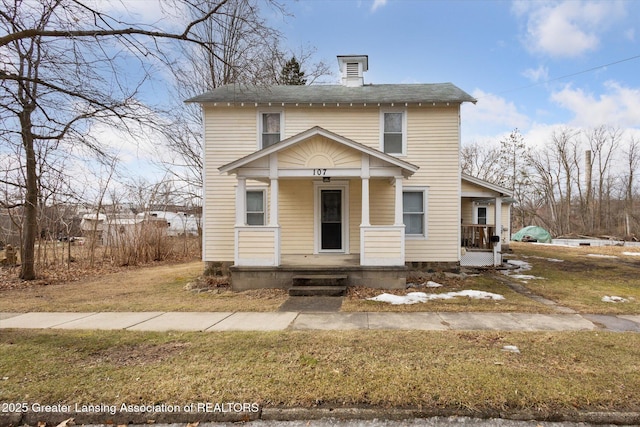 traditional style home with a porch, a chimney, and a front lawn