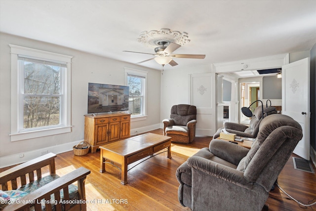 living area featuring ceiling fan, baseboards, visible vents, and light wood-style floors