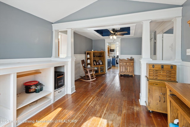 interior space with a ceiling fan, wainscoting, hardwood / wood-style floors, vaulted ceiling, and ornate columns