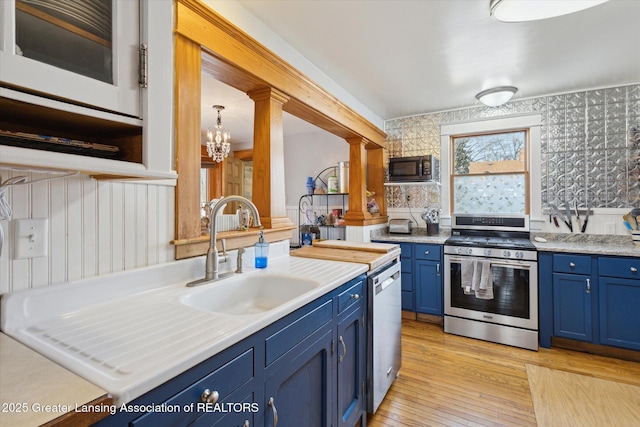 kitchen featuring blue cabinets, stainless steel appliances, a sink, light wood-type flooring, and decorative columns