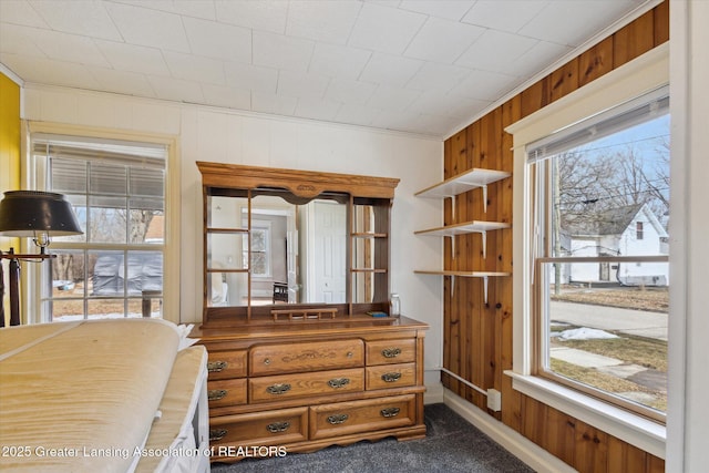 bedroom featuring ornamental molding, dark carpet, and wooden walls