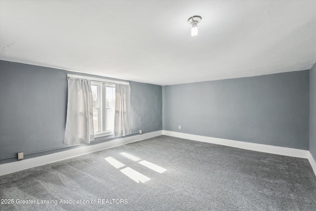 carpeted empty room featuring baseboards