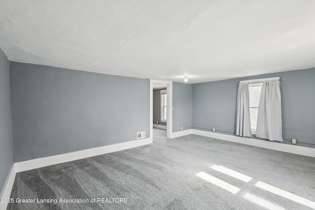 carpeted empty room featuring visible vents and baseboards